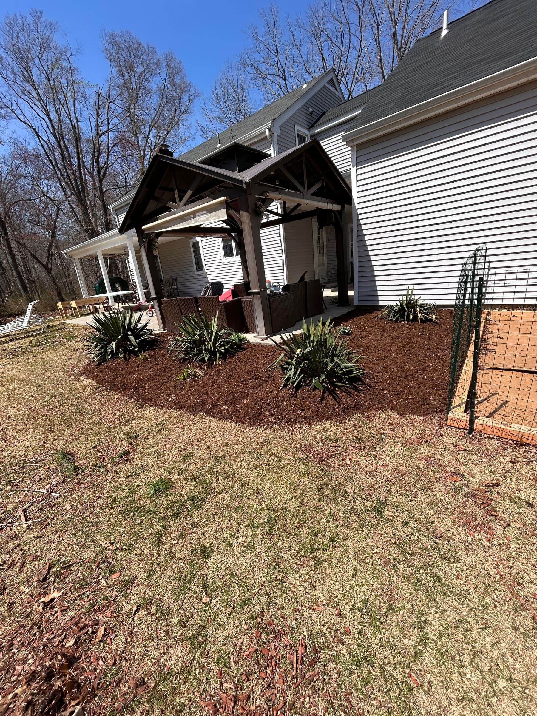 Freshly mulched bed planted with ornamental grasses curving around the side of a Connecticut home